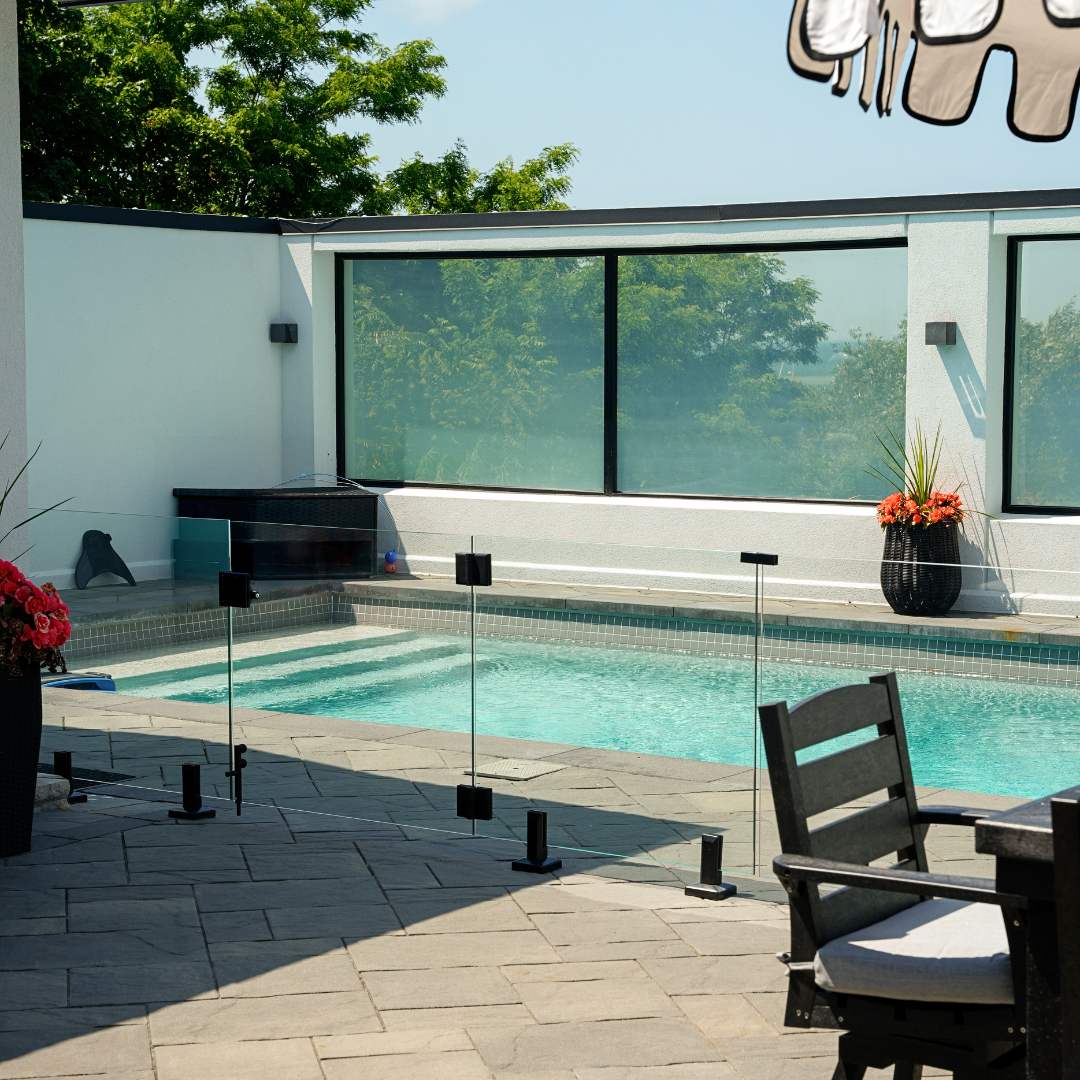 Glass pool fence enclosing an outdoor swimming pool for safety