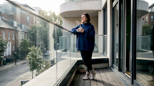 Homeowner viewing city through glass balcony panels
