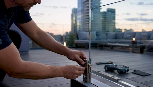 Installer securing glass railing panel outdoors