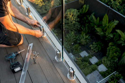 Contractor installing glass railing outdoors