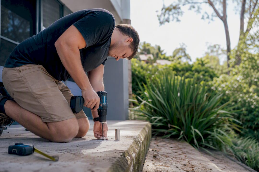 Worker drilling concrete slab for glass railing