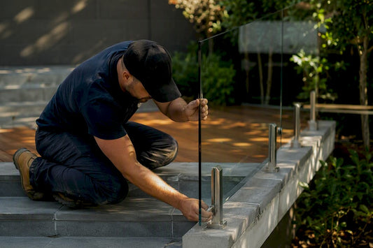 Installer mounting frameless glass railing panel on stairs