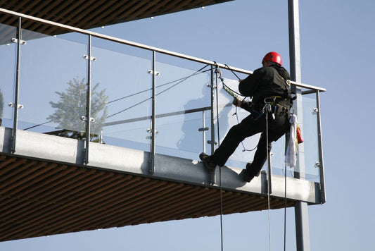 construction worker installing a glass railing system on a balcony