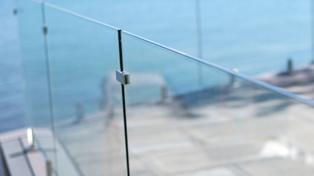 Frameless glass railing with a glass-to-glass clamp and slim top rail on a deck overlooking the water