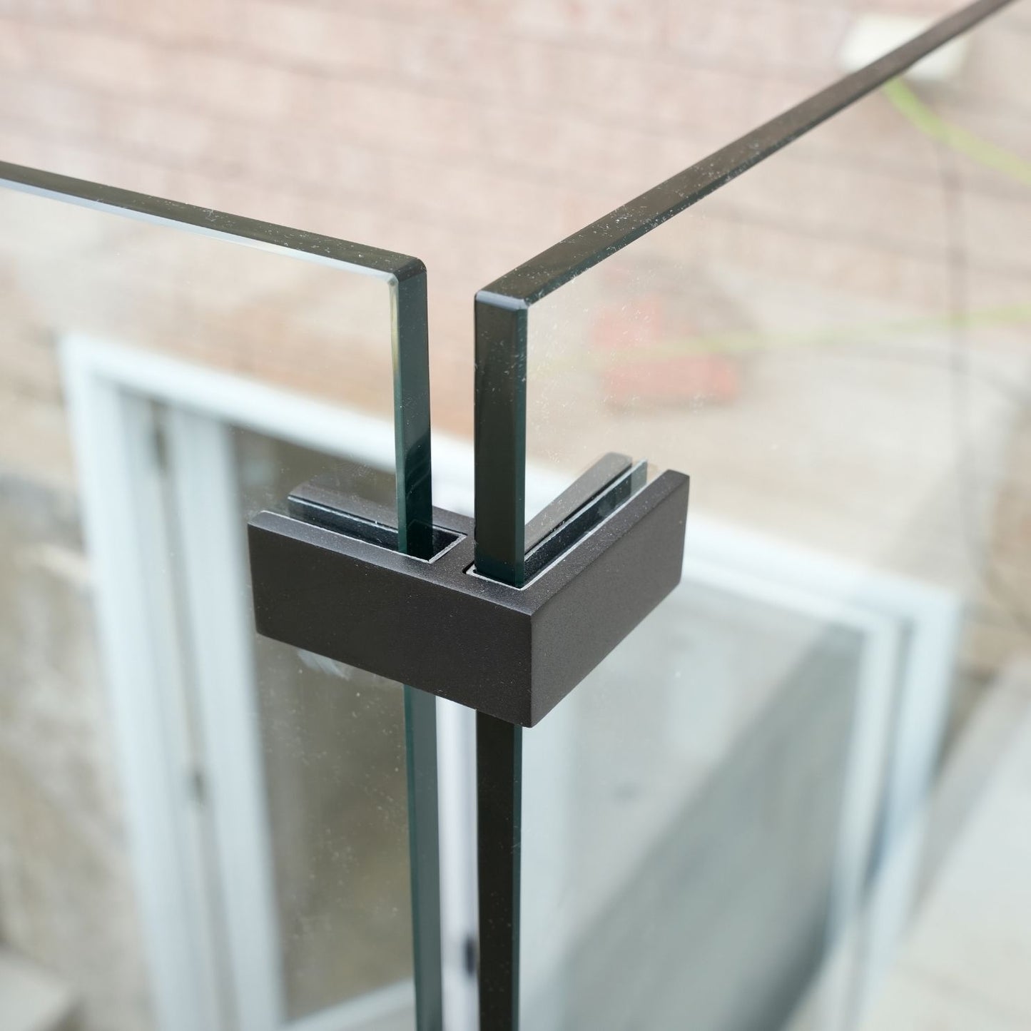 Ninety degree glass-to-glass connector joining two tempered glass panels at a railing corner