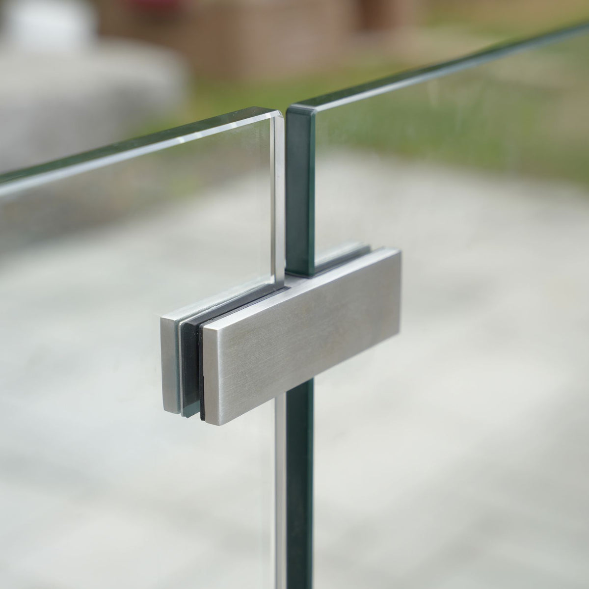Brushed stainless steel 180° glass-to-glass connector joining two frameless glass railing panels in a straight line