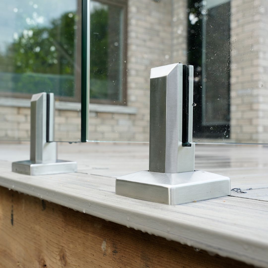 Brushed stainless spigot gripping a 12mm tempered glass railing panel