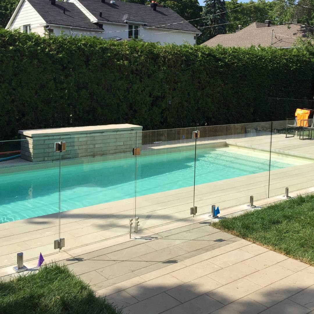 Frameless glass pool railing around a modern backyard pool