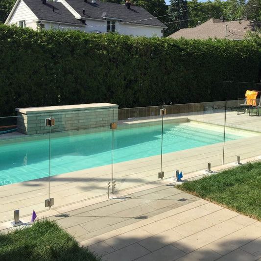 Frameless glass pool railing around a modern backyard pool