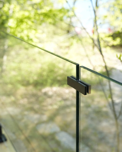 Matte black 180° glass-to-glass connector near the top of two 12mm glass railing panels