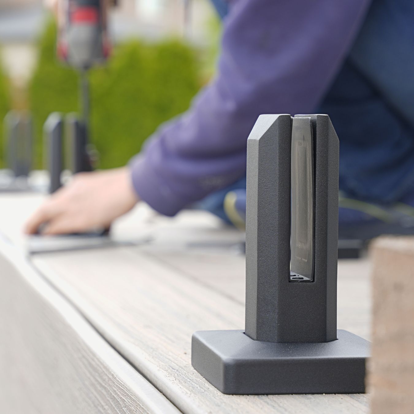 Two matte black spigots supporting a glass panel on a wood deck