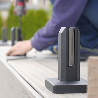 Two matte black spigots supporting a glass panel on a wood deck